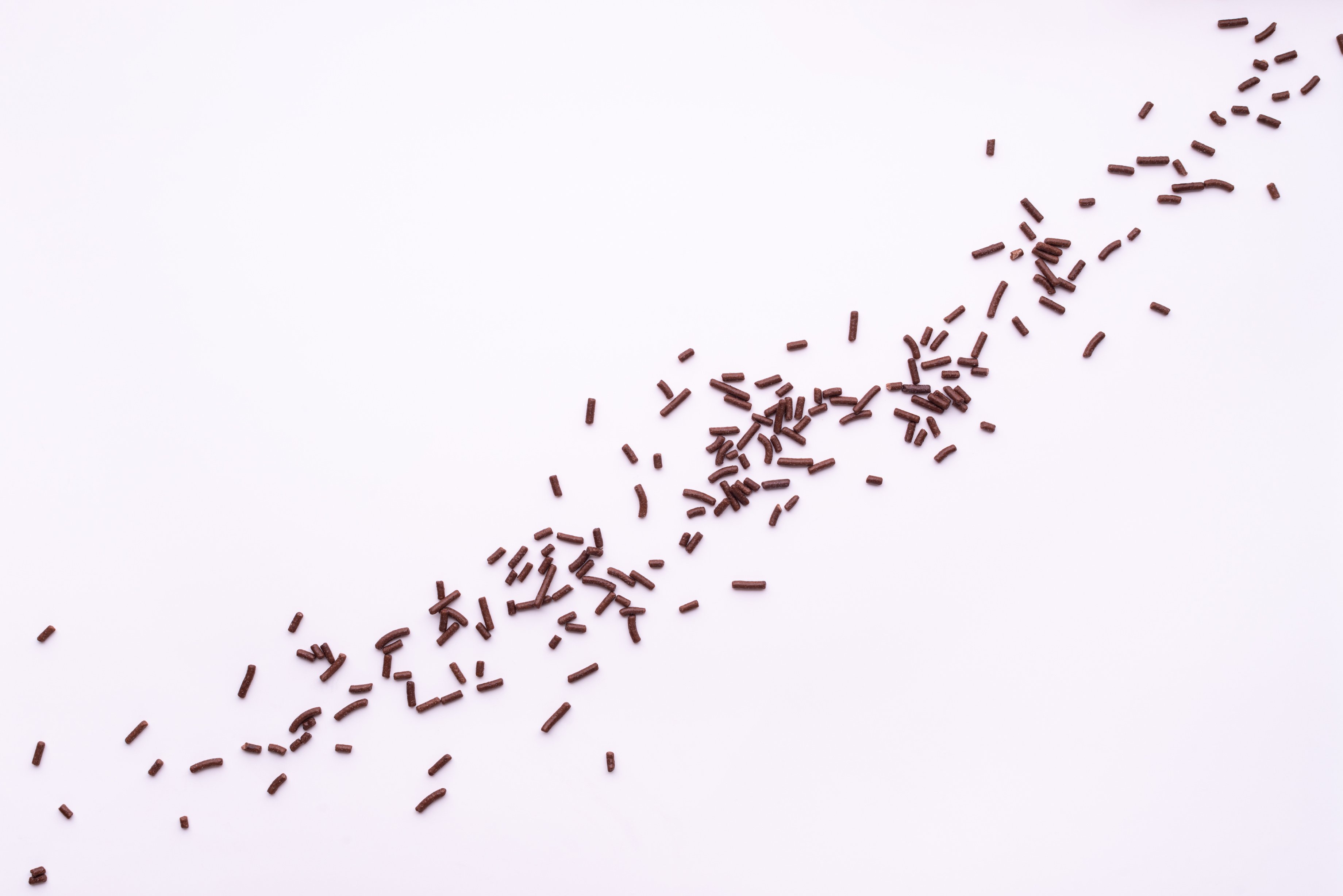 chocolate sprinkles over white background, flat lay